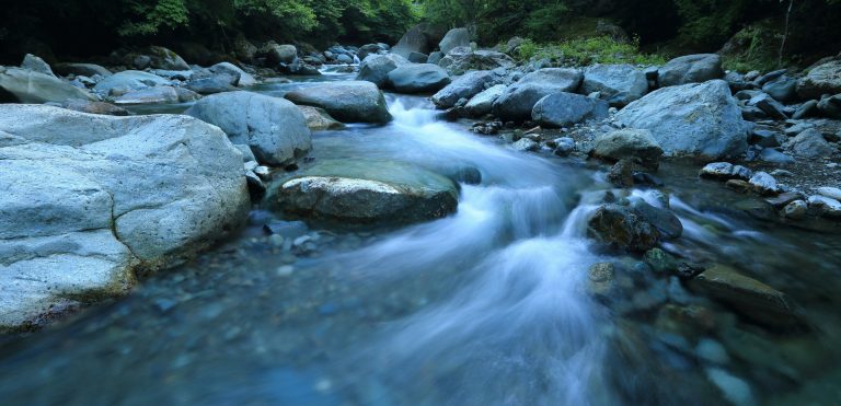 Clear mountain stream flowing over smooth rocks.