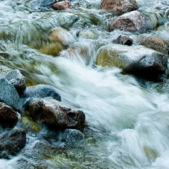 Clear mountain stream flowing over smooth rocks.